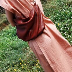 woman in a pink dress with a leather clutch in a flower field