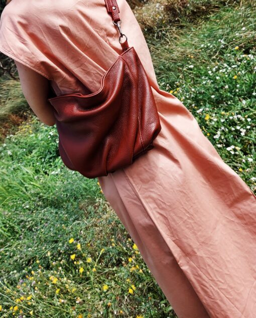 woman in a pink dress with a leather clutch in a flower field