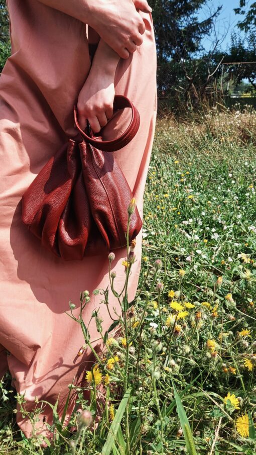 hand of a woman holding a leather clutch in a flower